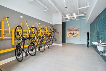 A room with several bikes hanging on a wall and a bathroom with sinks